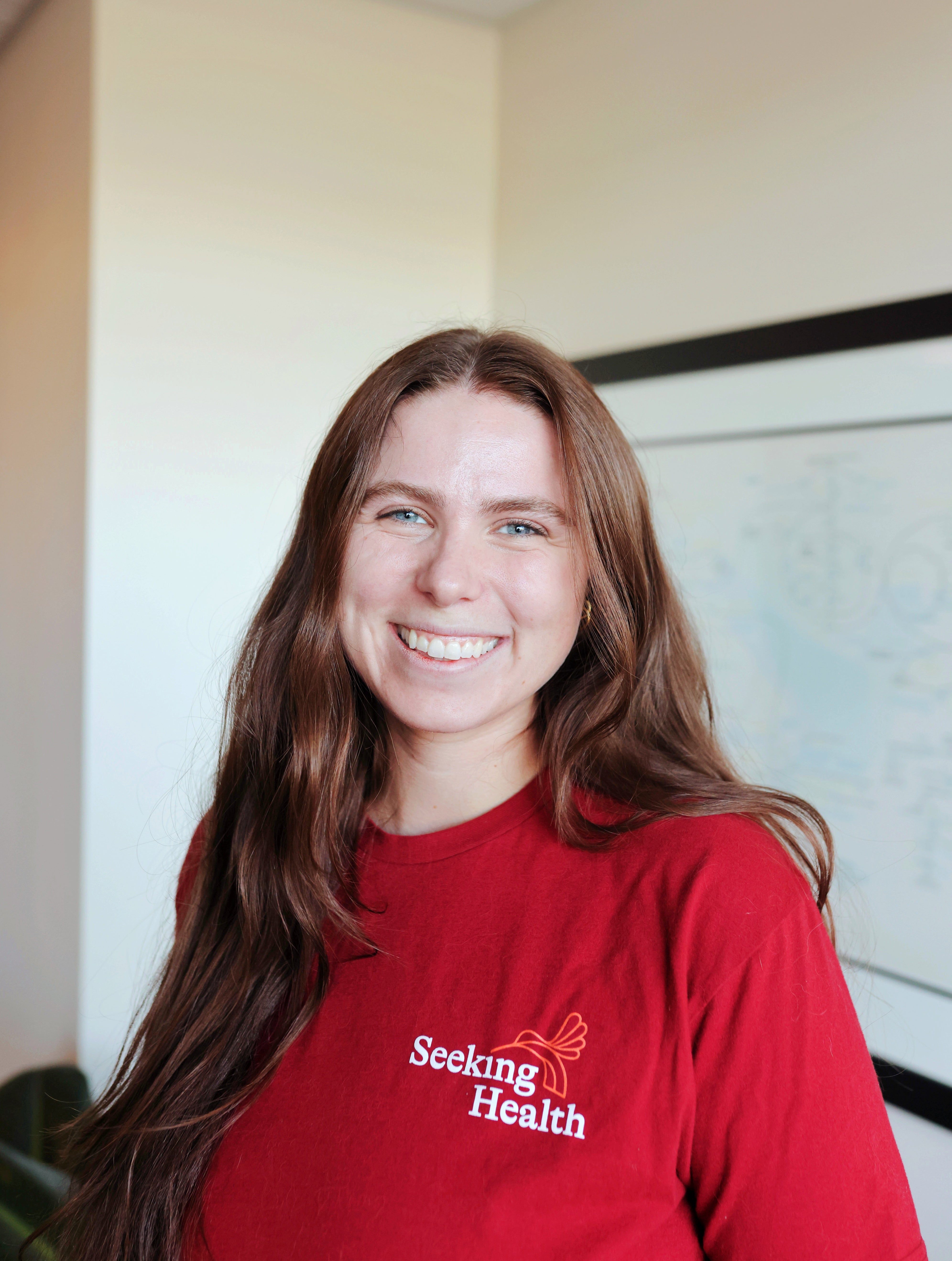Person wearing a red 'Seeking Health' shirt indoors